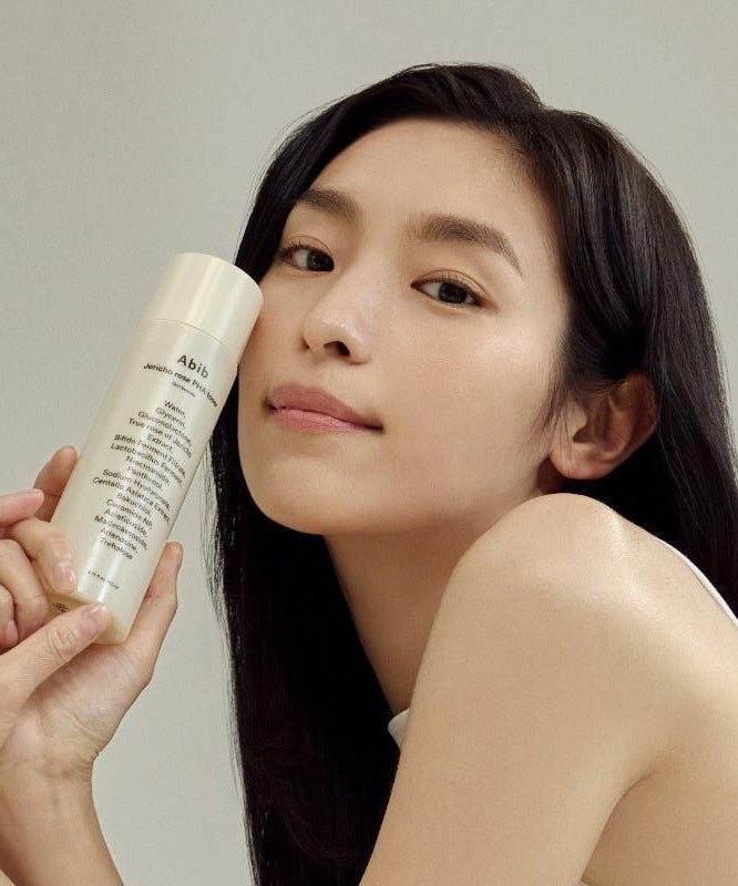 Person holding ABIB Jericho Rose PHA Toner Skin Booster 200ml near face for skincare routine.