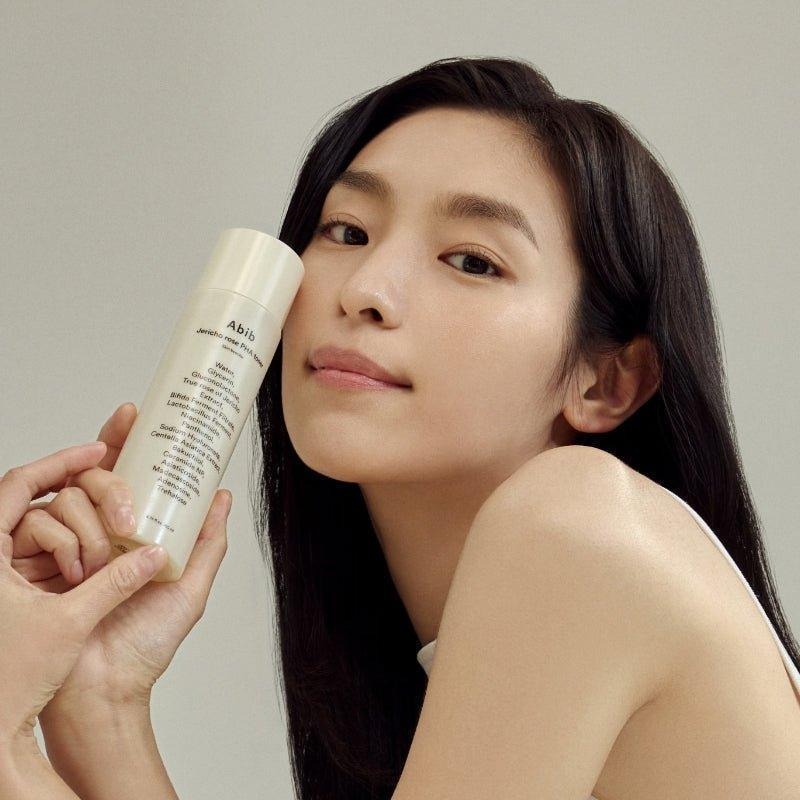 Person holding ABIB Jericho Rose PHA Toner Skin Booster 200ml near face for skincare routine.