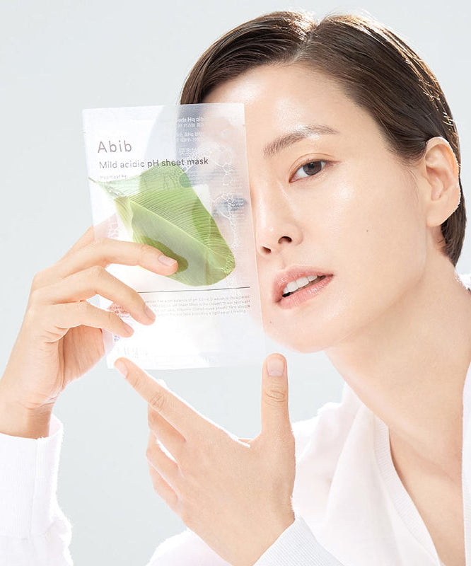 Person holding ABIB Mild Acidic pH Sheet Mask 30ml with clear packaging and green leaf design