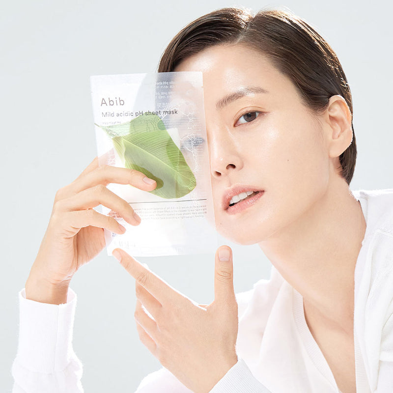 Person holding ABIB Mild Acidic pH Sheet Mask 30ml with clear packaging and green leaf design