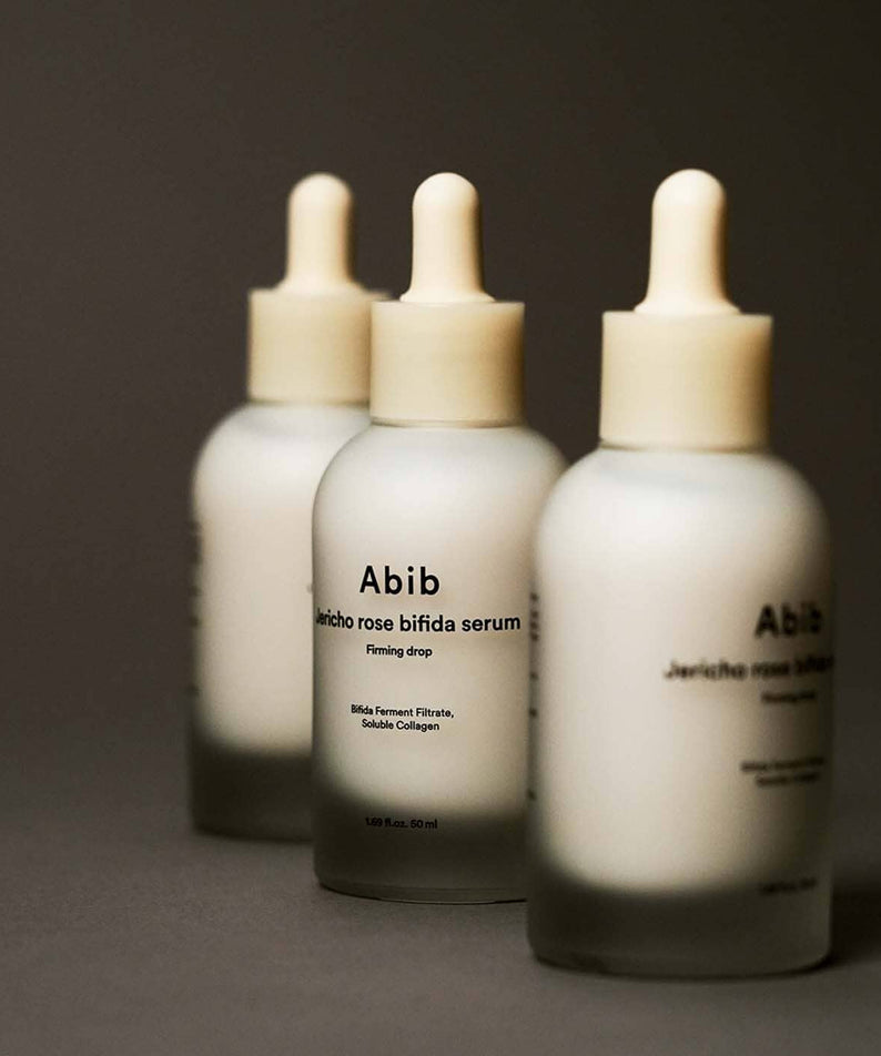 Three bottles of ABIB Resurrection Bifida Serum Firming Drops 50ml displayed on a dark background.