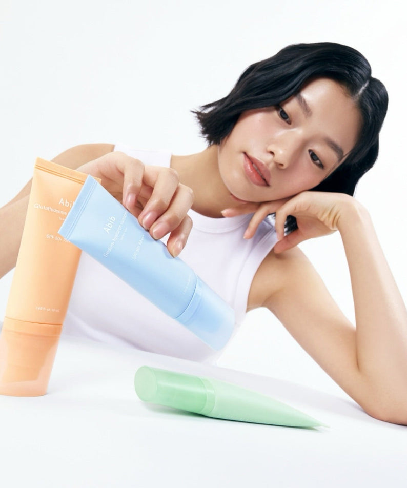 ABIB Sunscreen Tube 50ml 3 Types displayed with model holding the blue tube, showcasing different sunscreen options.