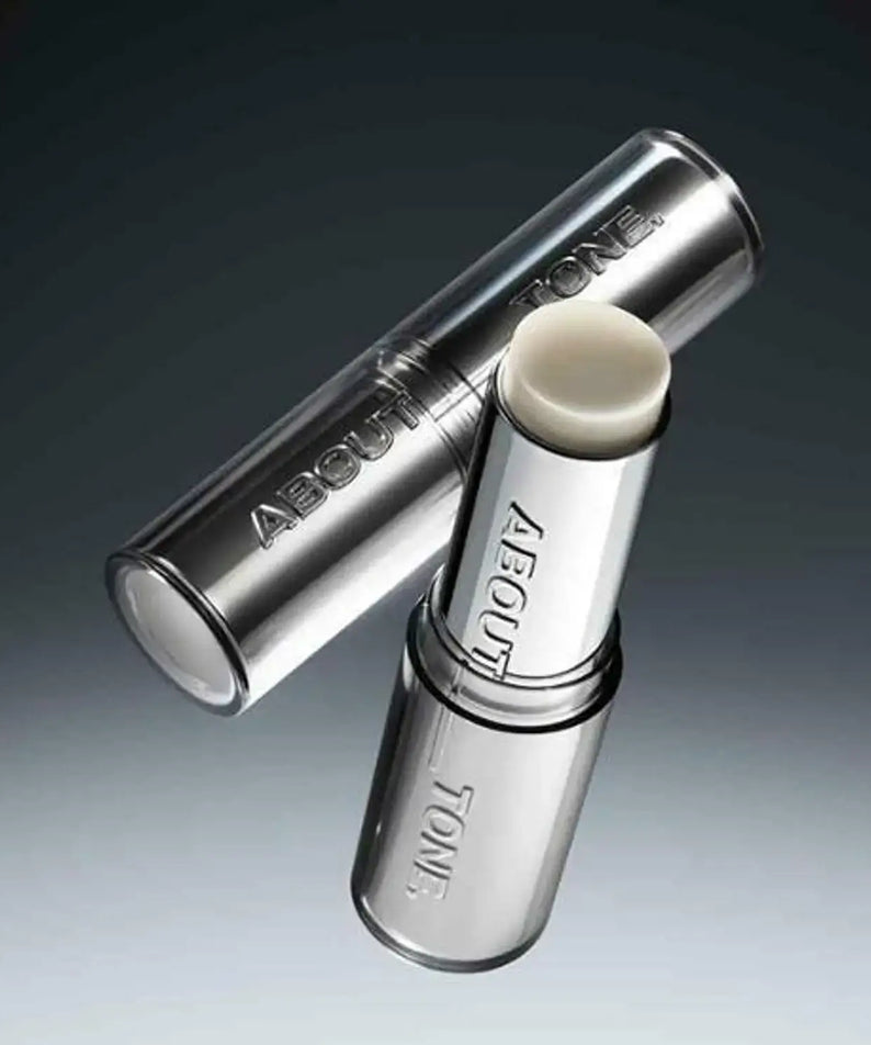 Close-up of the ABOUT TONE Blur Lasting Stick Primer in sleek packaging on a dark gradient background.