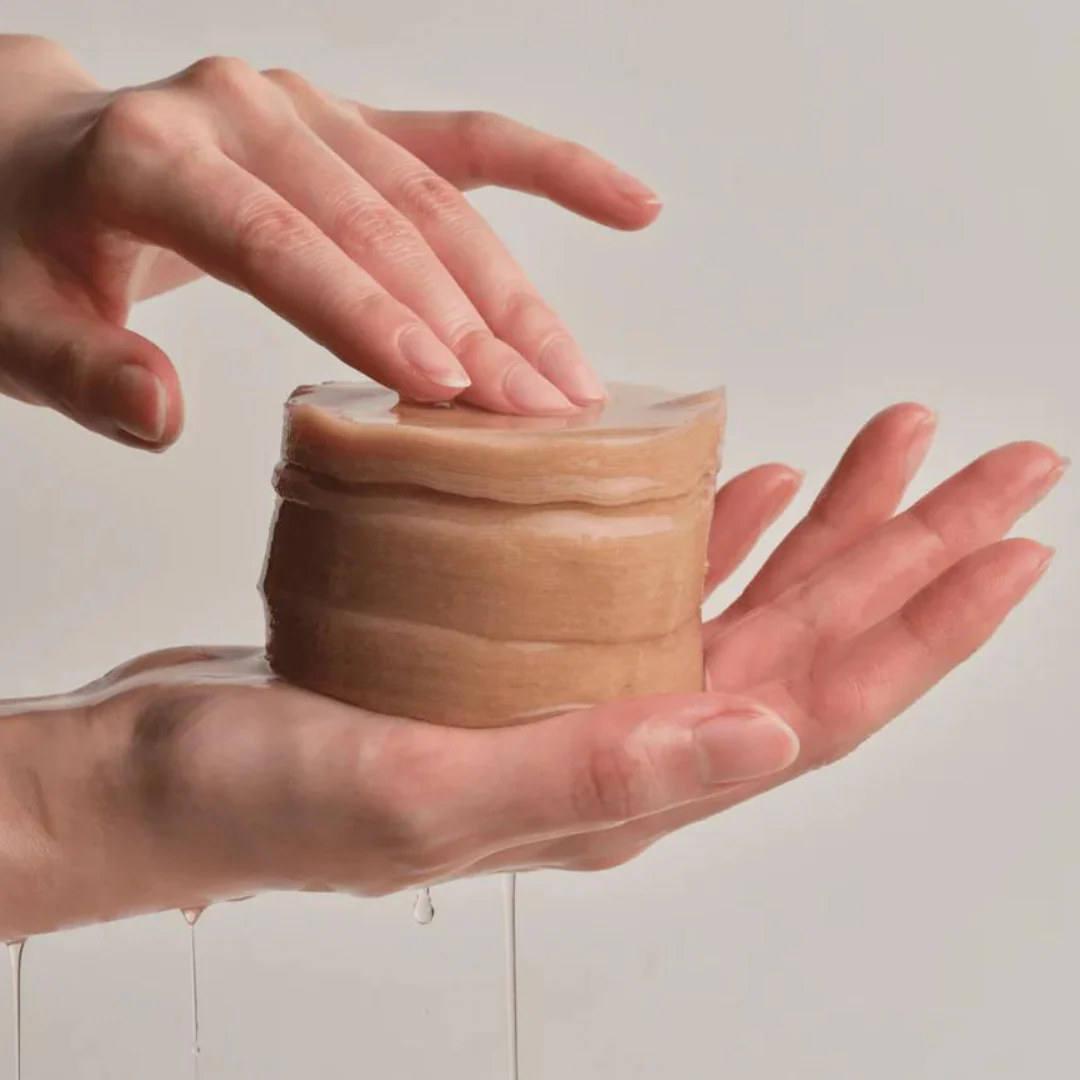 Hands holding a stack of ACWELL Licorice pH Balancing Toner Pad 70P with liquid dripping