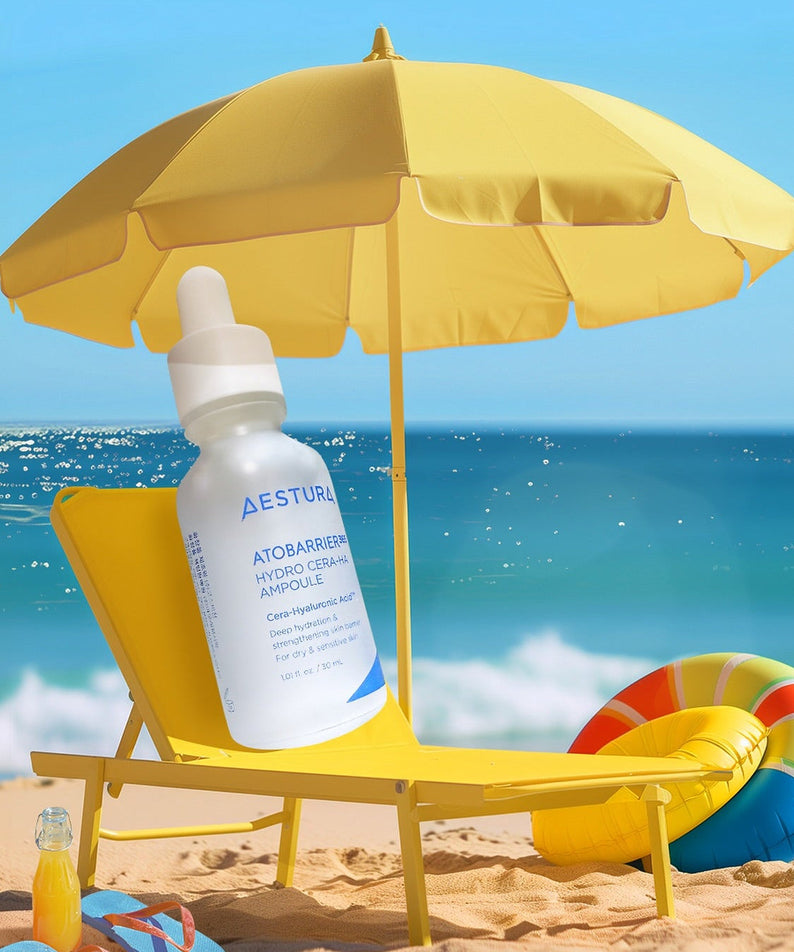 AESTURA Atobarrier 365 Hydro Cera-HA Ampoule 30ml displayed on a sunny beach with yellow umbrella and chair.
