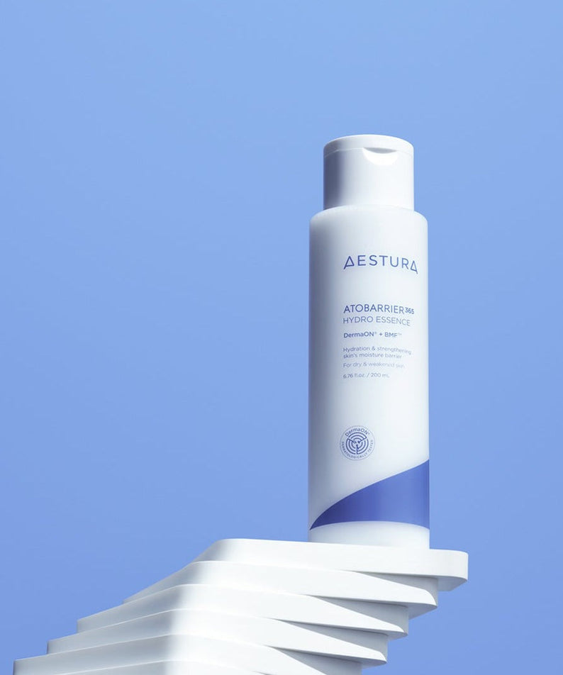 AESTURA Atobarrier 365 Hydro Essence 200ml bottle against a blue background, showcasing its sleek design and skincare branding.