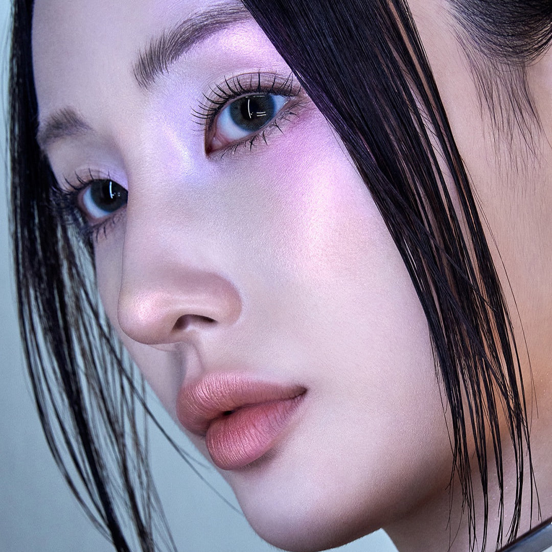 Close-up portrait of a woman with iridescent makeup and sleek black hair