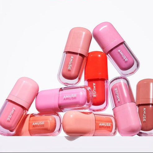 Collection of colorful AMUSE BEBE TINT lip products in various shades displayed neatly in a pyramid arrangement.