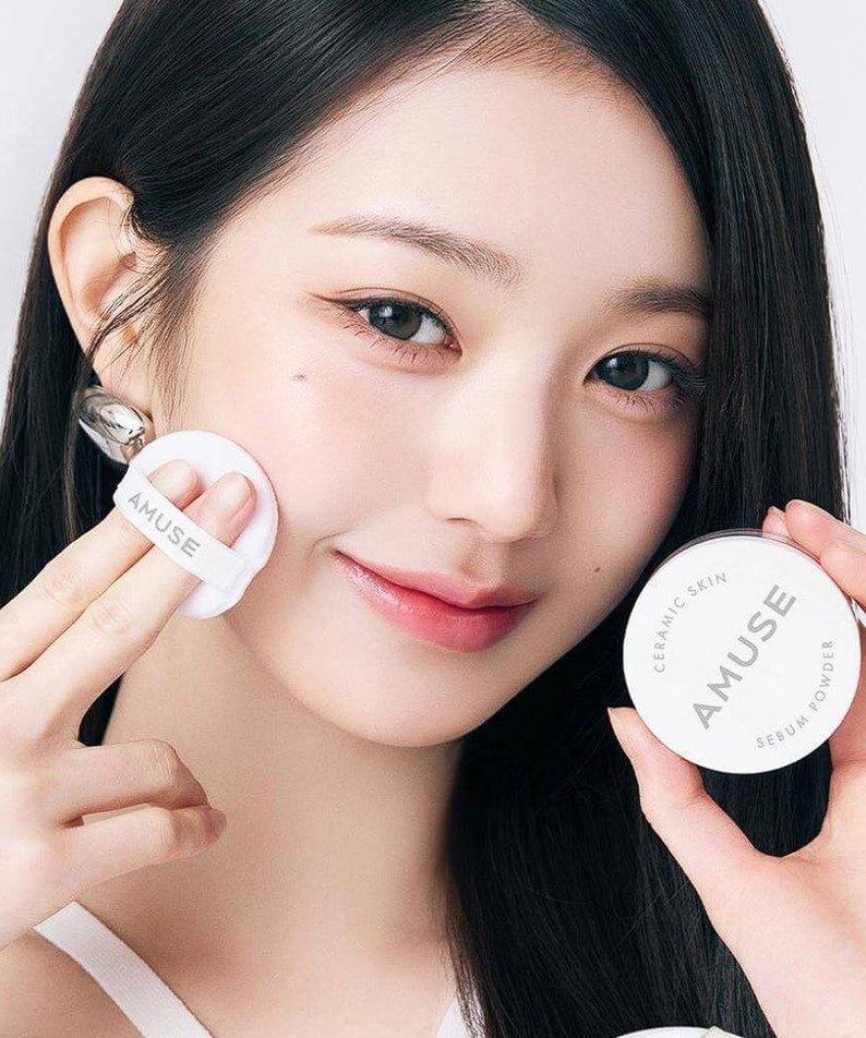 Woman applying AMUSE Ceramic Sebum Powder with puff applicator.