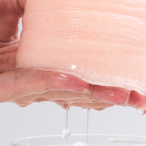 Sheet of AND:AR Centellian in Cica Calming Pads 70 sheets being squeezed with liquid dripping into a container.