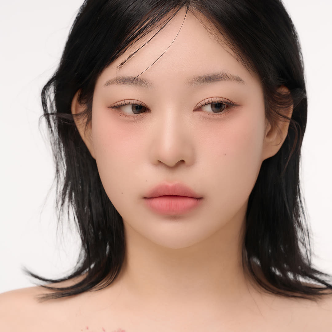 Model wearing natural makeup look with soft pink lips and subtle eye makeup