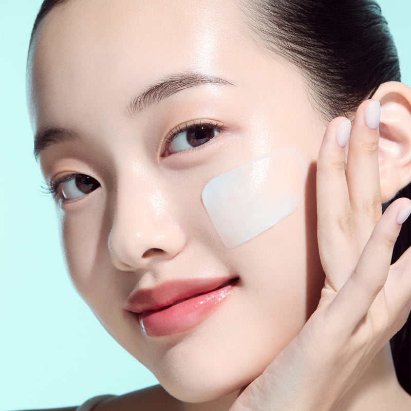 Woman applying skincare product to face on a light blue background.