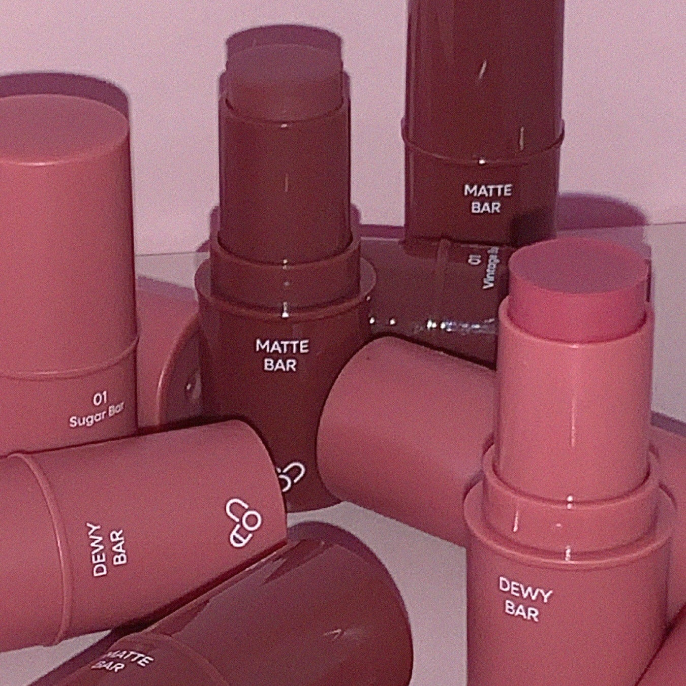 Assorted AOU Matte Bar and Dewy Bar lipsticks displayed on a reflective surface.