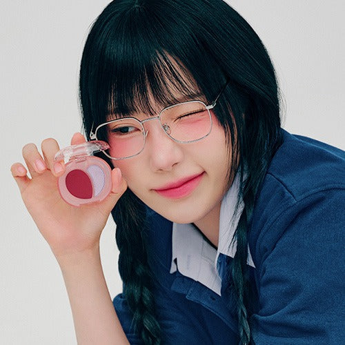 Woman holding A'PIEU Juicy Pang Mood Blending Lip & Cheek Balm, smiling and winking