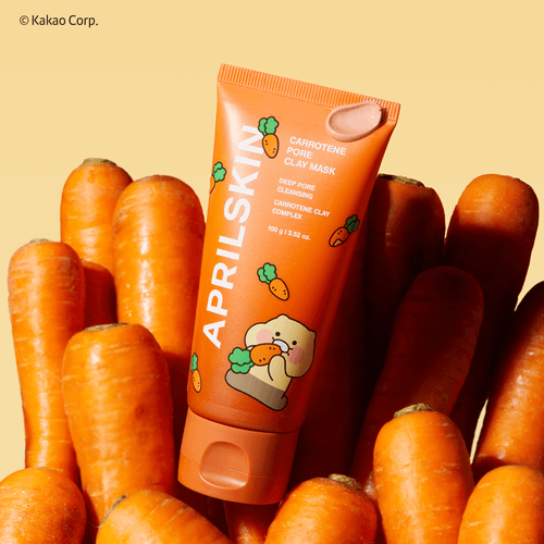 APRILSKIN Carrotene Pore Clay Mask tube surrounded by fresh carrots, showcasing deep pore cleansing and carrotene clay complex.