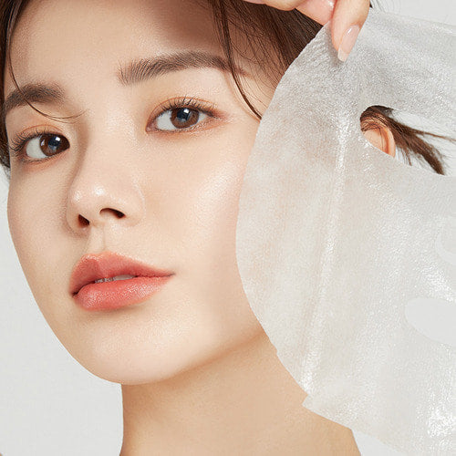Woman applying APRILSKIN Carrotent IPMP Calming & Hydrating Sheets Mask to her face.