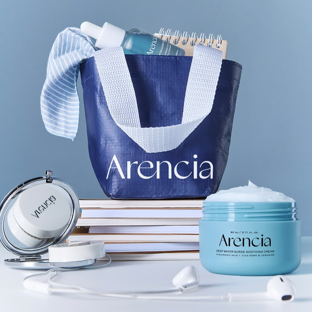 ARENCIA Deep Water Surge Soothing Cream 80ml jar beside a blue tote with skincare products and a notebook on a table.