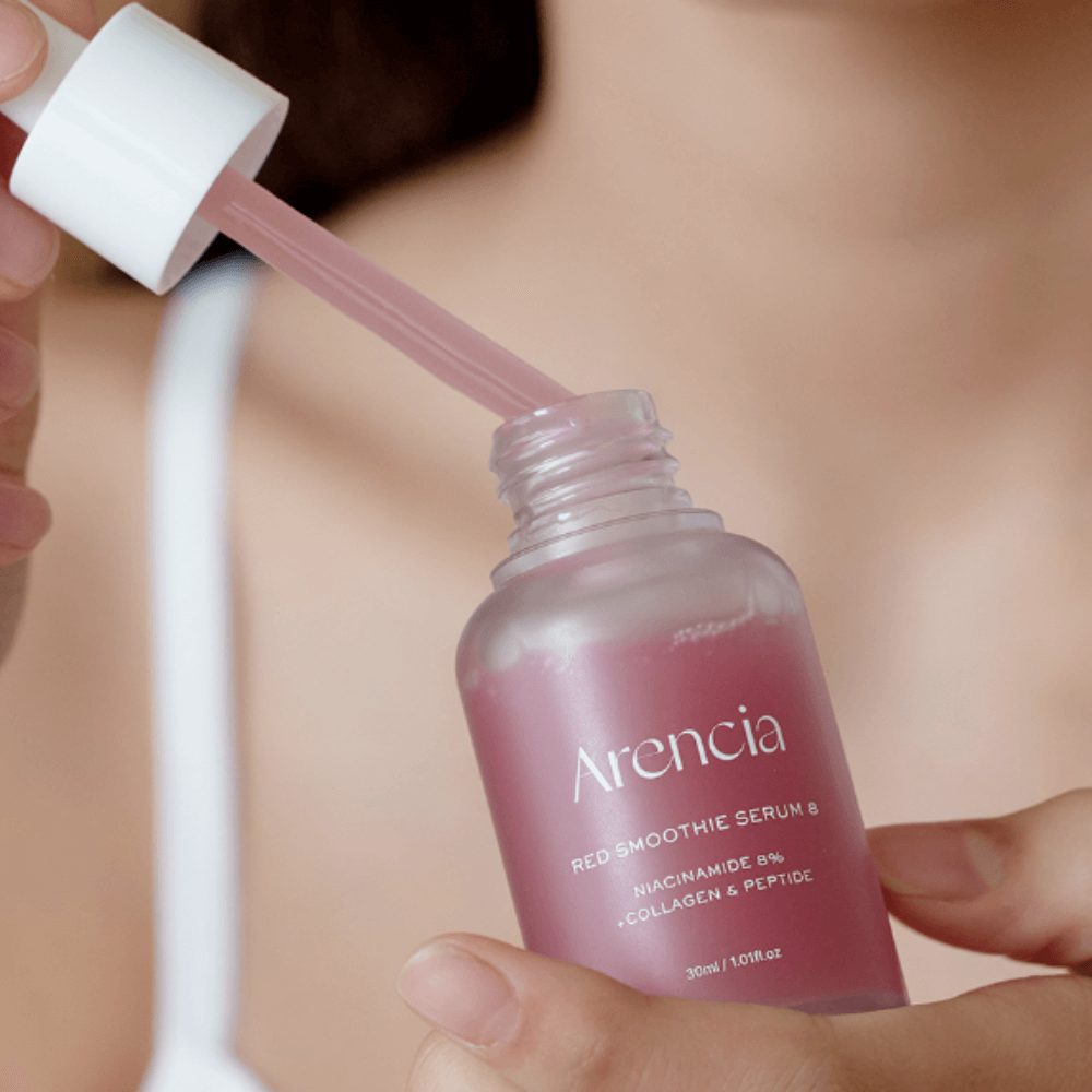 Person applying ARENCIA Red Smoothie Serum 8 30ml from a dropper bottle.
