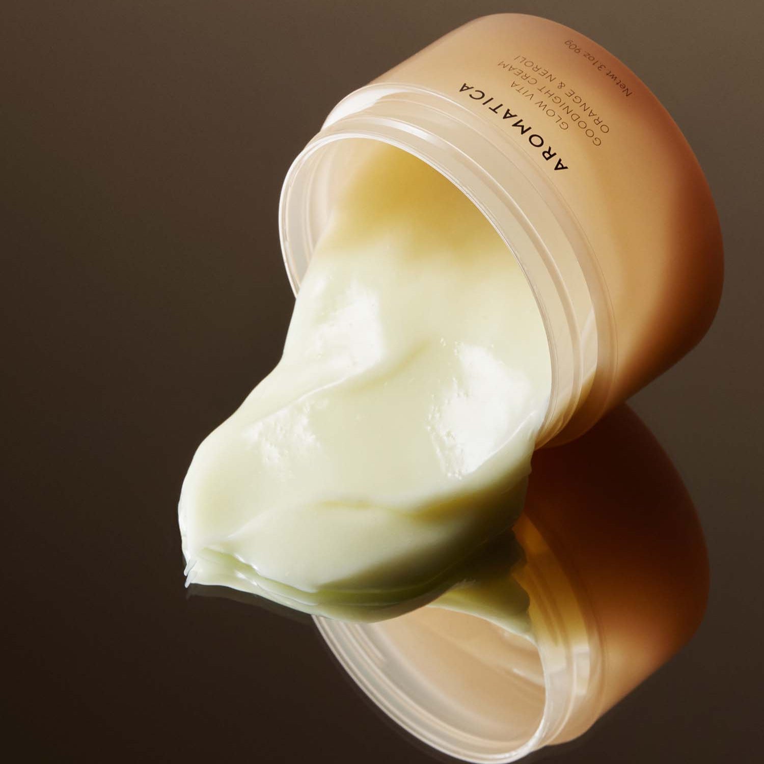 AROMATICA Glow Vita Good Night Cream Orange & Neroli 90G jar with cream spilling out on glossy surface