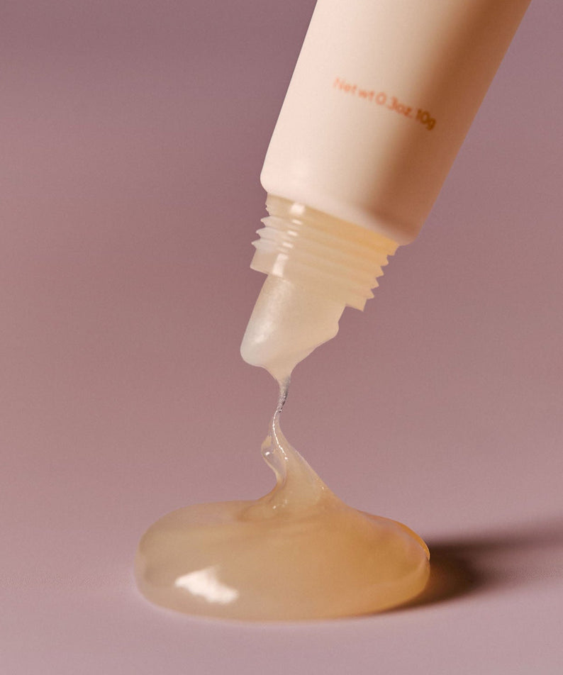 Close-up of AROMATICA Glow Vita Lip Volumizer Orange & Neroli dripping from tube, showing rich texture.