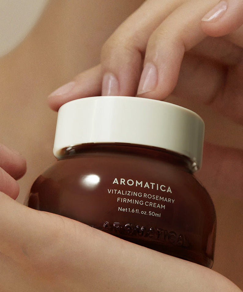 Hands holding AROMATICA Vitalizing Rosemary Firming Cream 50ML jar