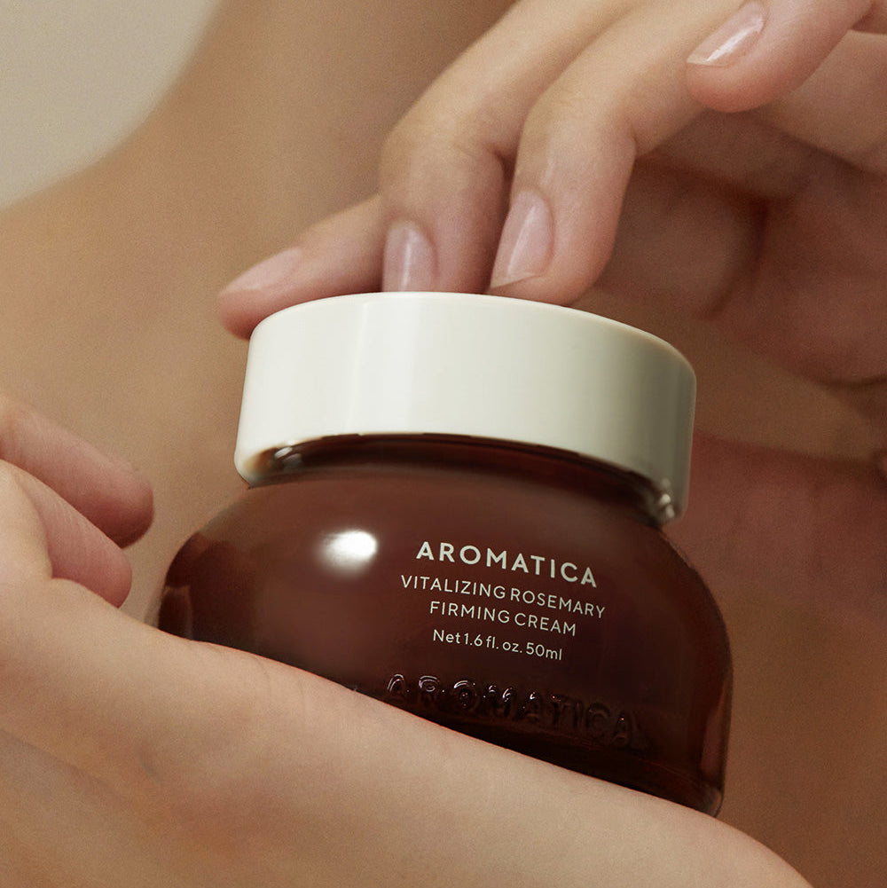 Hands holding AROMATICA Vitalizing Rosemary Firming Cream 50ML jar