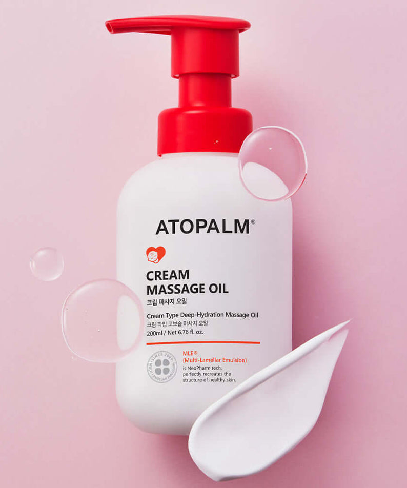 ATOPALM Cream Massage Oil 200ml bottle on a pink background with cream and oil droplets