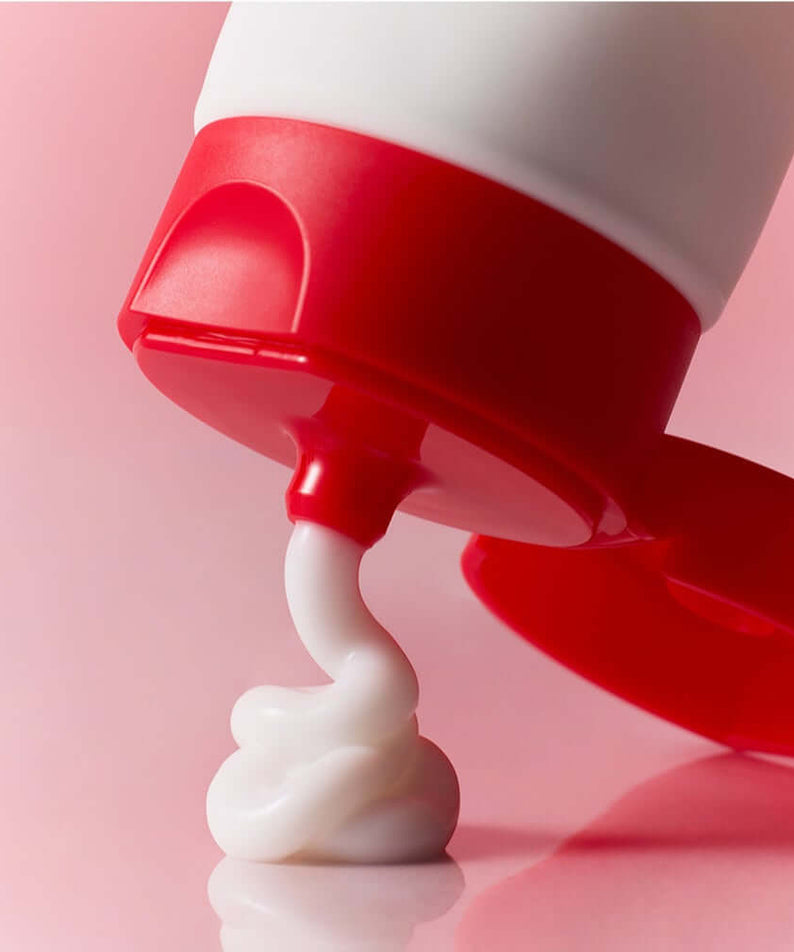 ATOPALM Face Lotion 80ml tube dispensing cream on a pink background