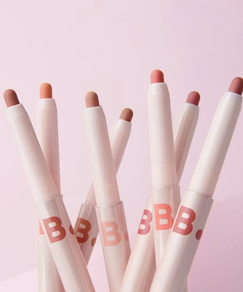 Assorted BANILA CO Smudging Lip Pencil shades displayed on pink background.