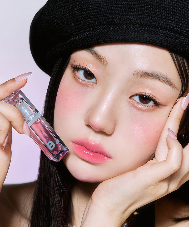 Person holding BANILA CO Volume Lip Plumper close to face, showcasing the product's packaging and color.