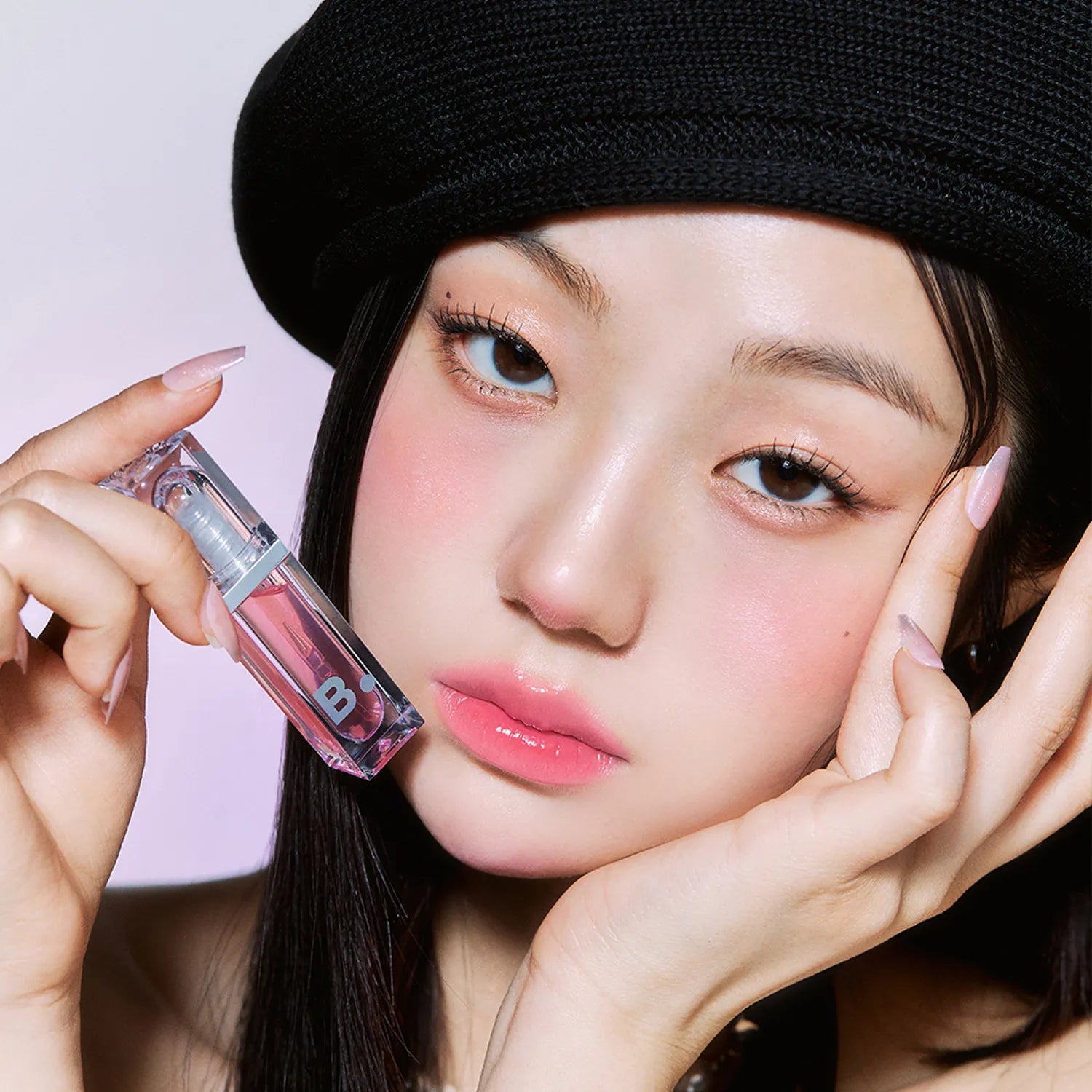 Person holding BANILA CO Volume Lip Plumper close to face, showcasing the product's packaging and color.
