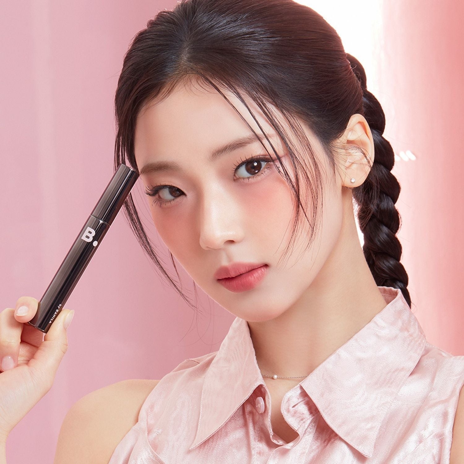 Model holding BANILACO Powerproof Mascara in elegant pink setting