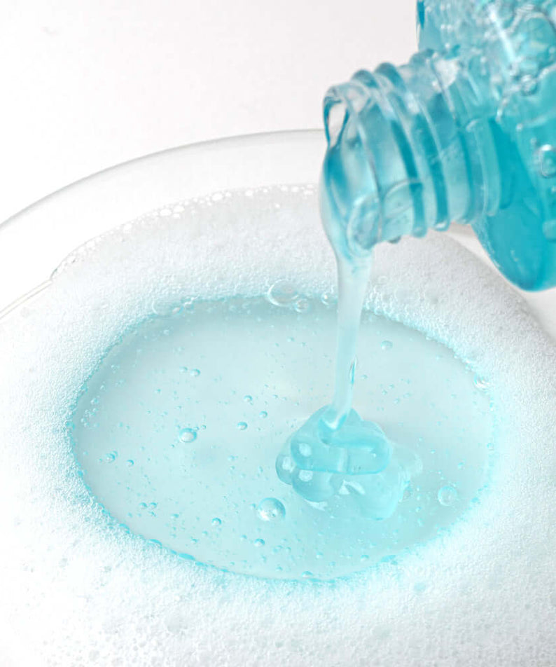 Pouring BARULAB 10-Hyaluronic Acid Blue Aqua Cleansing Gel into a bowl of bubbly foam, highlighting its hydrating properties