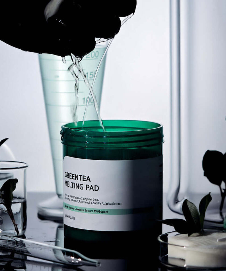 BARULAB Green Tea Melting Pad surrounded by lab equipment and green plants, illustrating skincare innovation and botanical infusion.