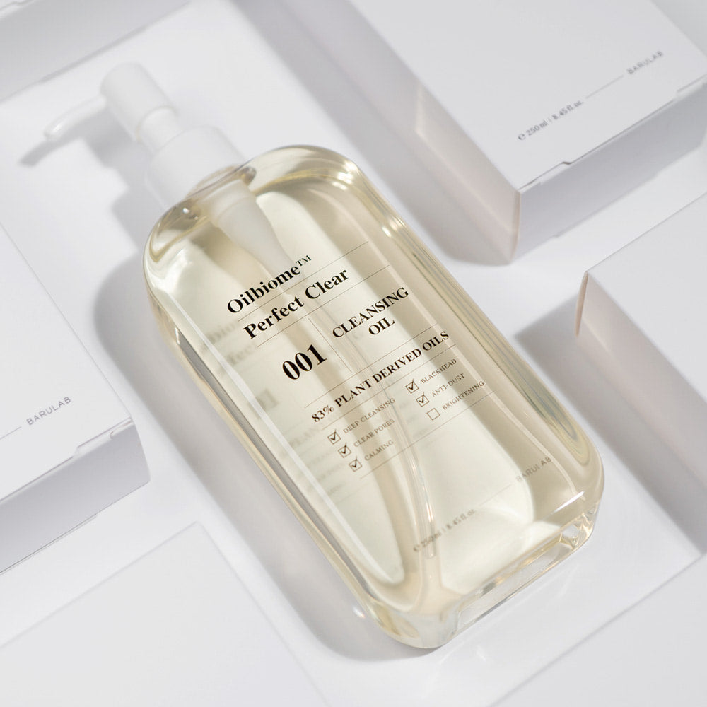 BARULAB Oilbiome Perfect Clear Cleansing Oil 250ml bottle in bright light surrounded by packaging, showcasing product design and clarity.