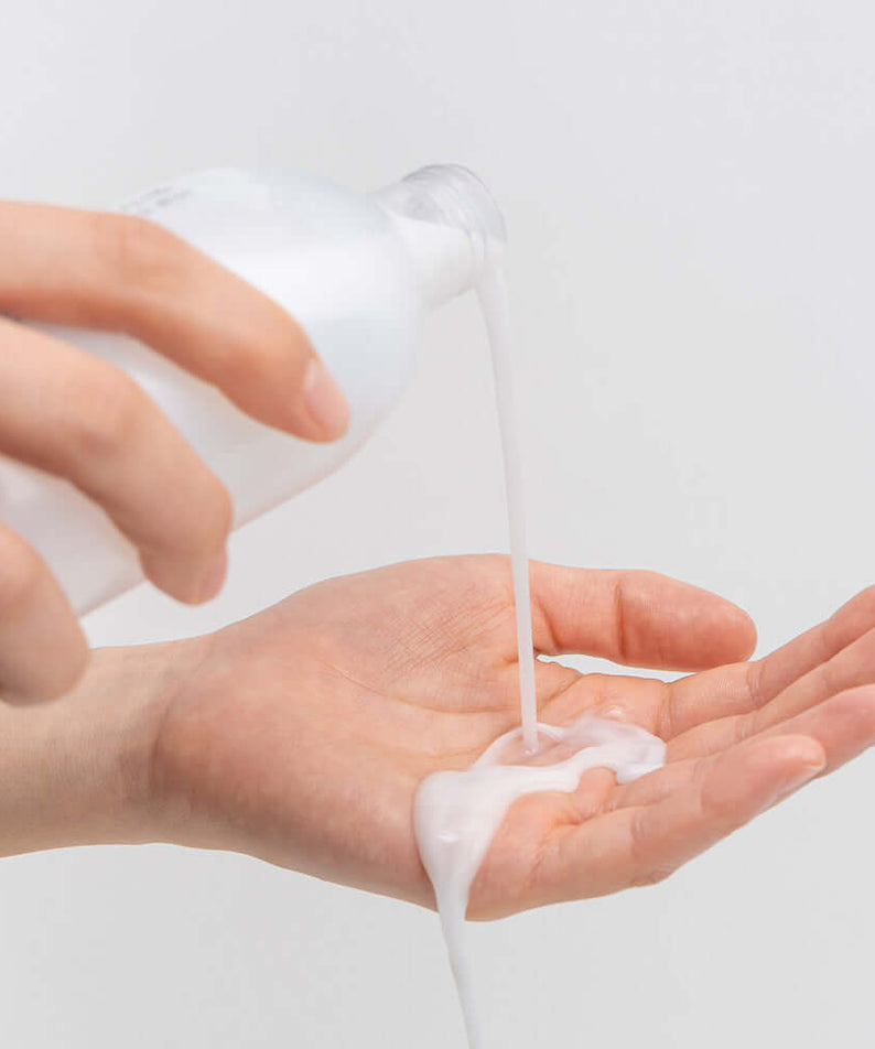 Pouring BARULAB Rice Makgeolli Probiotic Yeast Cream in Essence 200ml into hand for skincare routine.