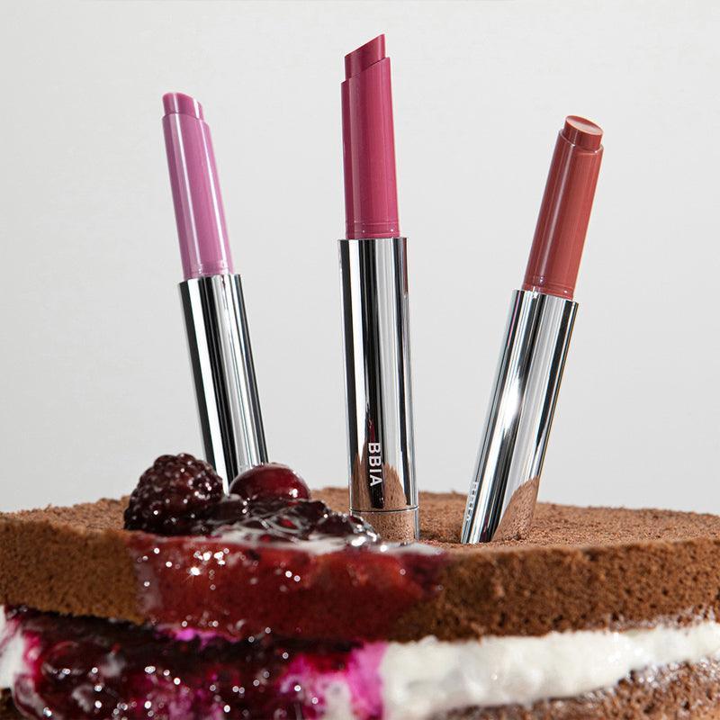 BBIA Over Glaze Stick displayed on a chocolate cake with berry topping, showcasing three vibrant shades in sleek packaging.
