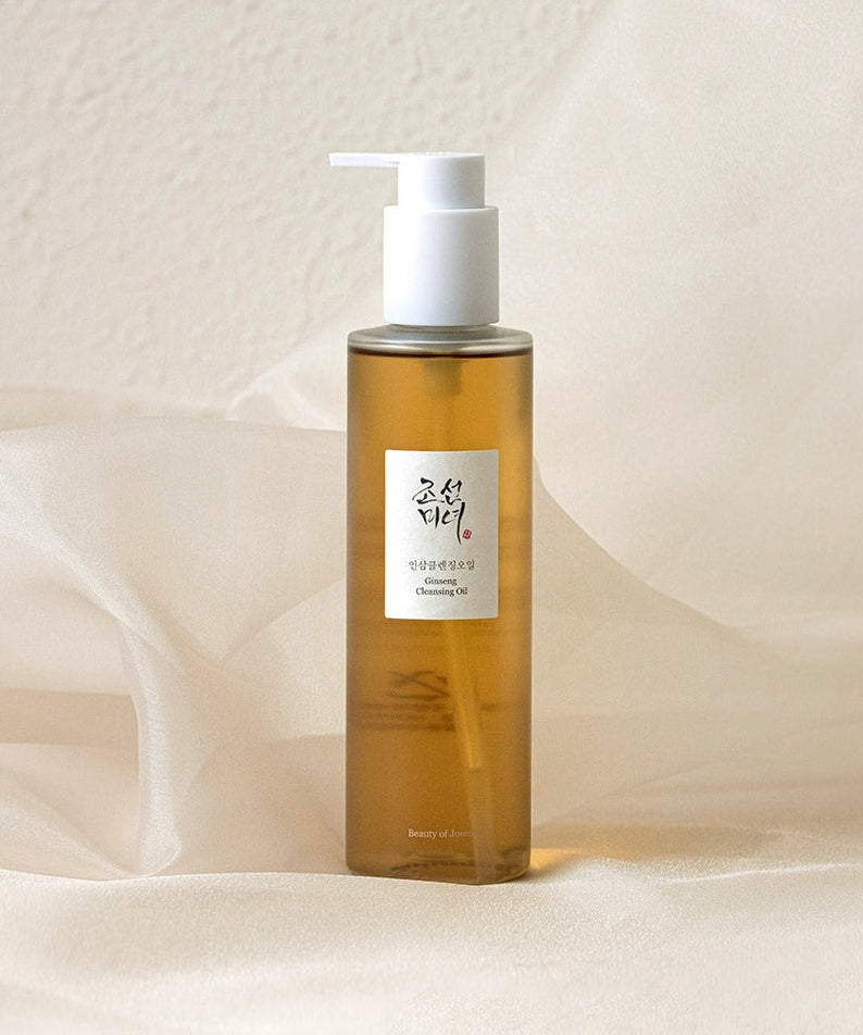 A bottle of BEAUTY OF JOSEON Ginseng Cleansing Oil 210ml on a soft fabric background.