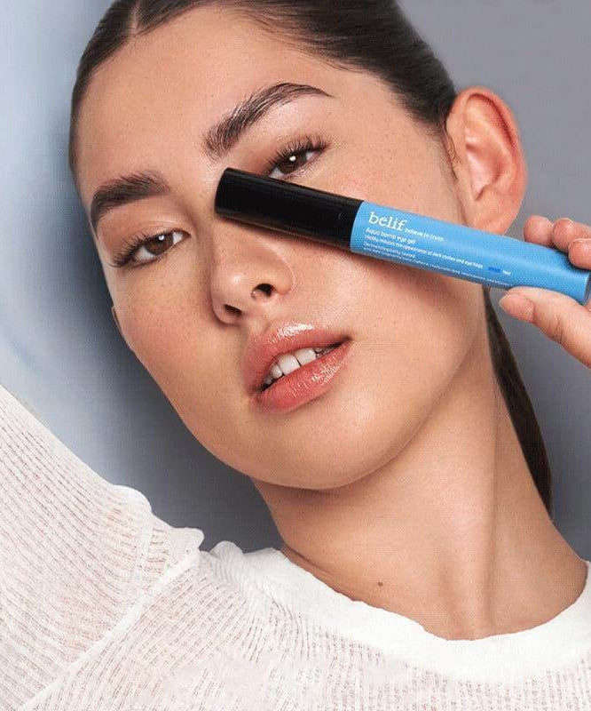 Model holding BELIF Aqua Bomb Eye Gel 15ml next to her face for skincare promotion.