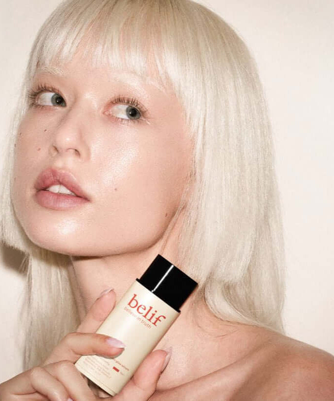 Model holding BELIF Super Drops Glow Serum 50ml for a radiant skincare routine.
