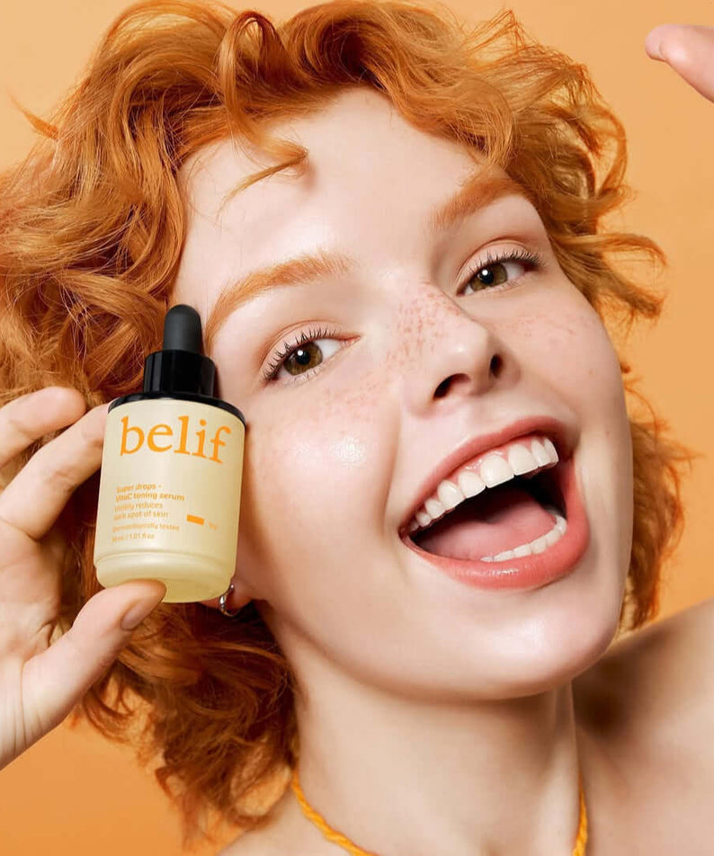 Woman smiling while holding BELIF Super Drops Vita C Toning Serum 30ml bottle