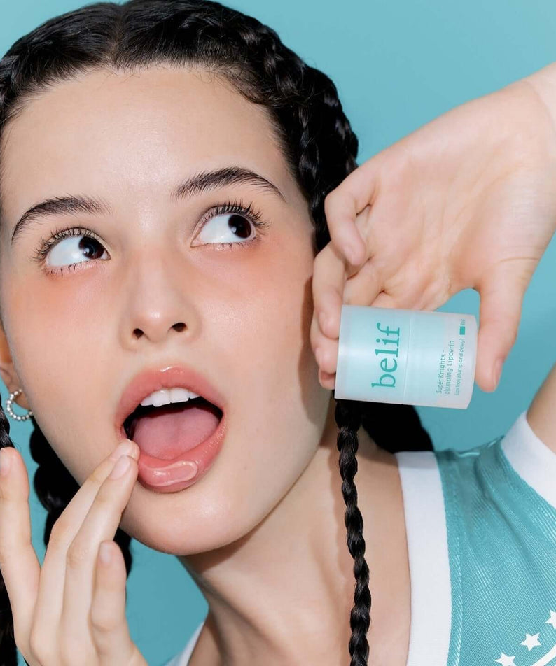Woman applying BELIF Super Knight Mint Plumping Lipcerine with an excited expression.