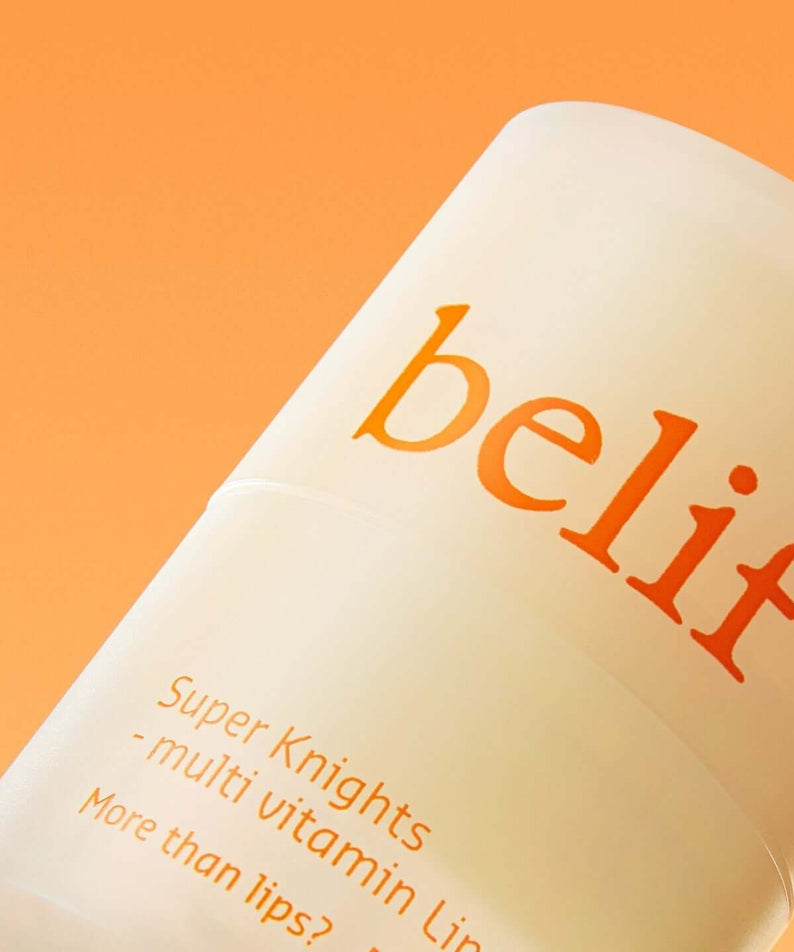 Close-up of BELIF Super Knight Multi Vitamin Lipcerin bottle against an orange background