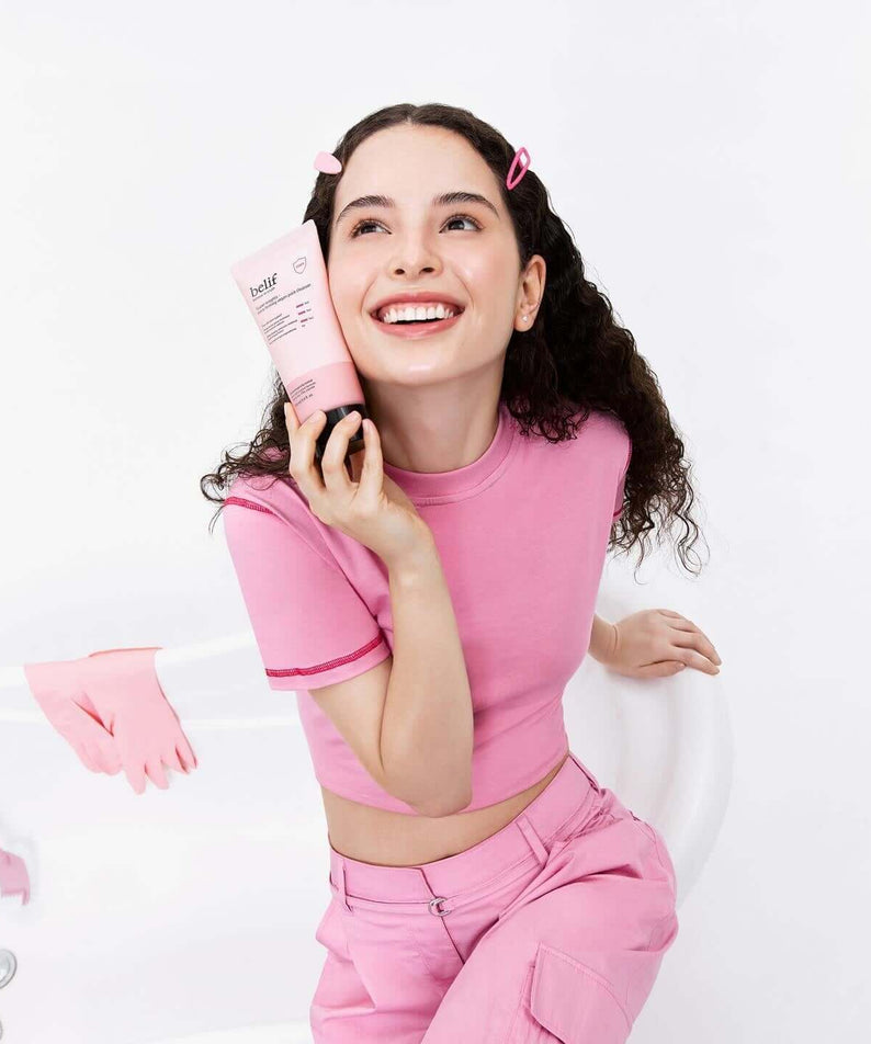 Smiling woman holding BELIF Super Knights Pore Fiming Vegan Pack Cleanser 150ml in a pink outfit.