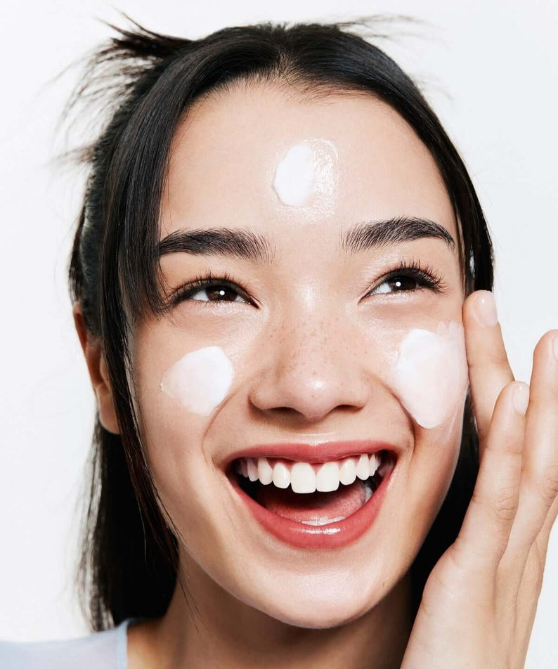 Smiling woman applying BELIF The True Cream Moisturizing Bomb 50ml on her face