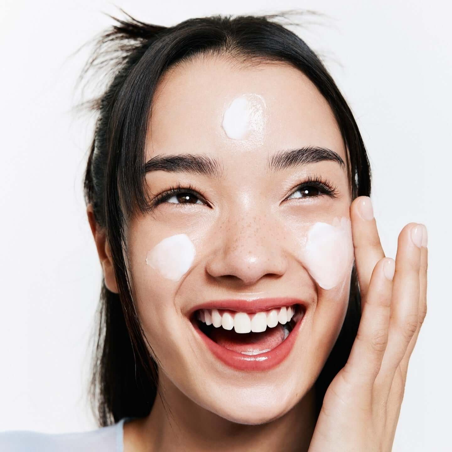 Smiling woman applying BELIF The True Cream Moisturizing Bomb 50ml on her face
