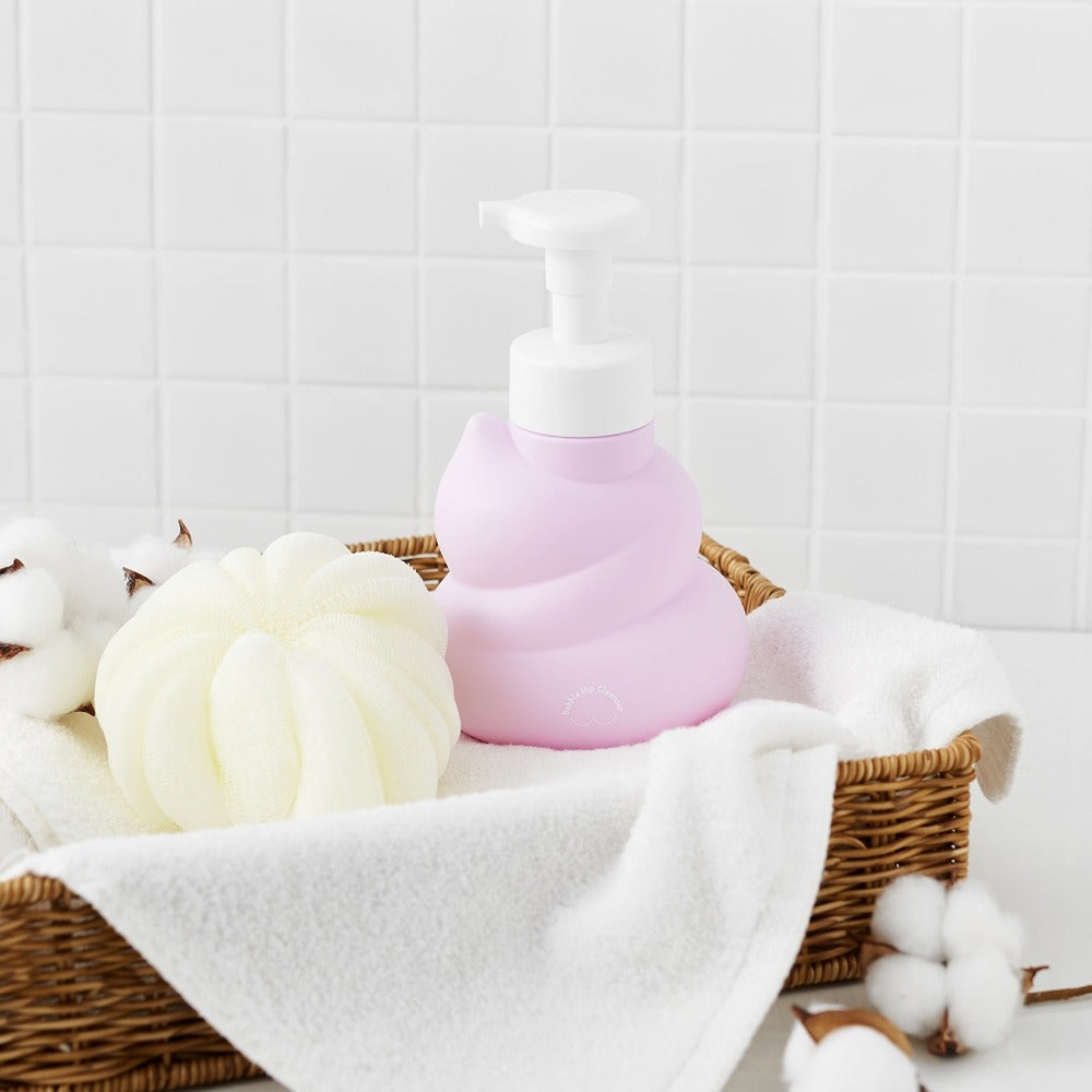 BELLBOY STUDIO Hippong Bubble Butt Cleanser bottle in a wicker basket with cotton and towels, showcasing bathroom decor and product display.