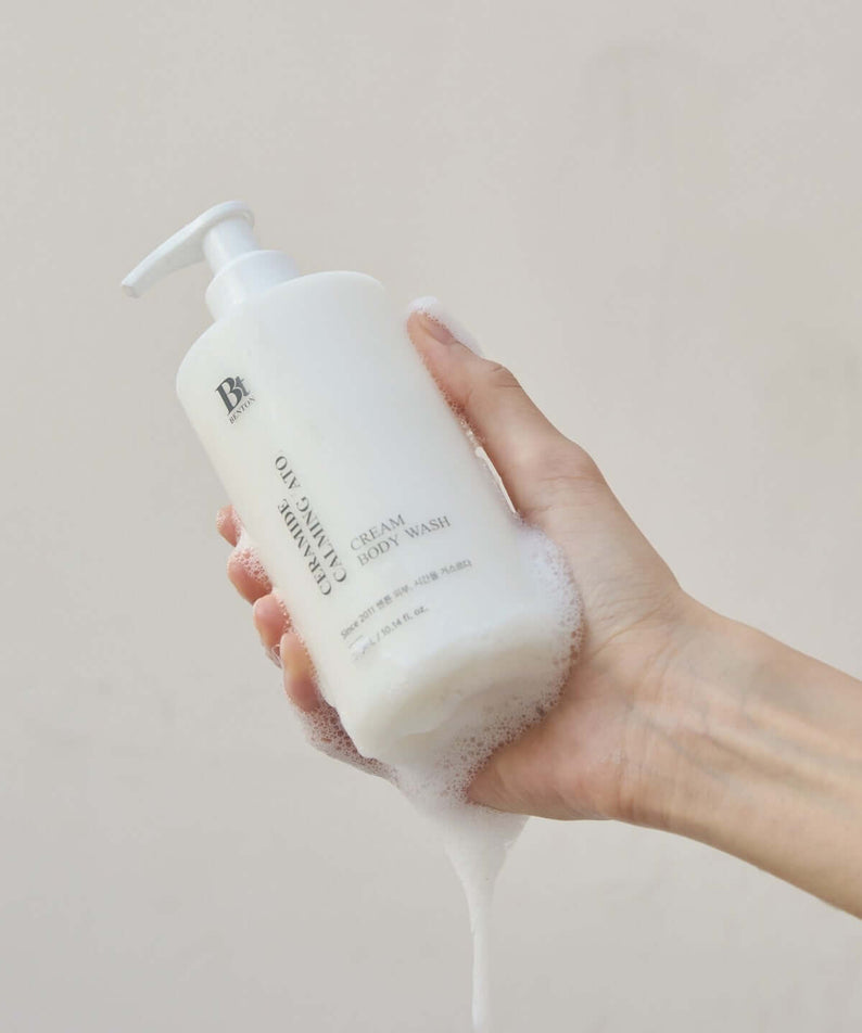 Hand holding BENTON Ceramide Calming Ato Cream Body Wash 300ml lathered in foam