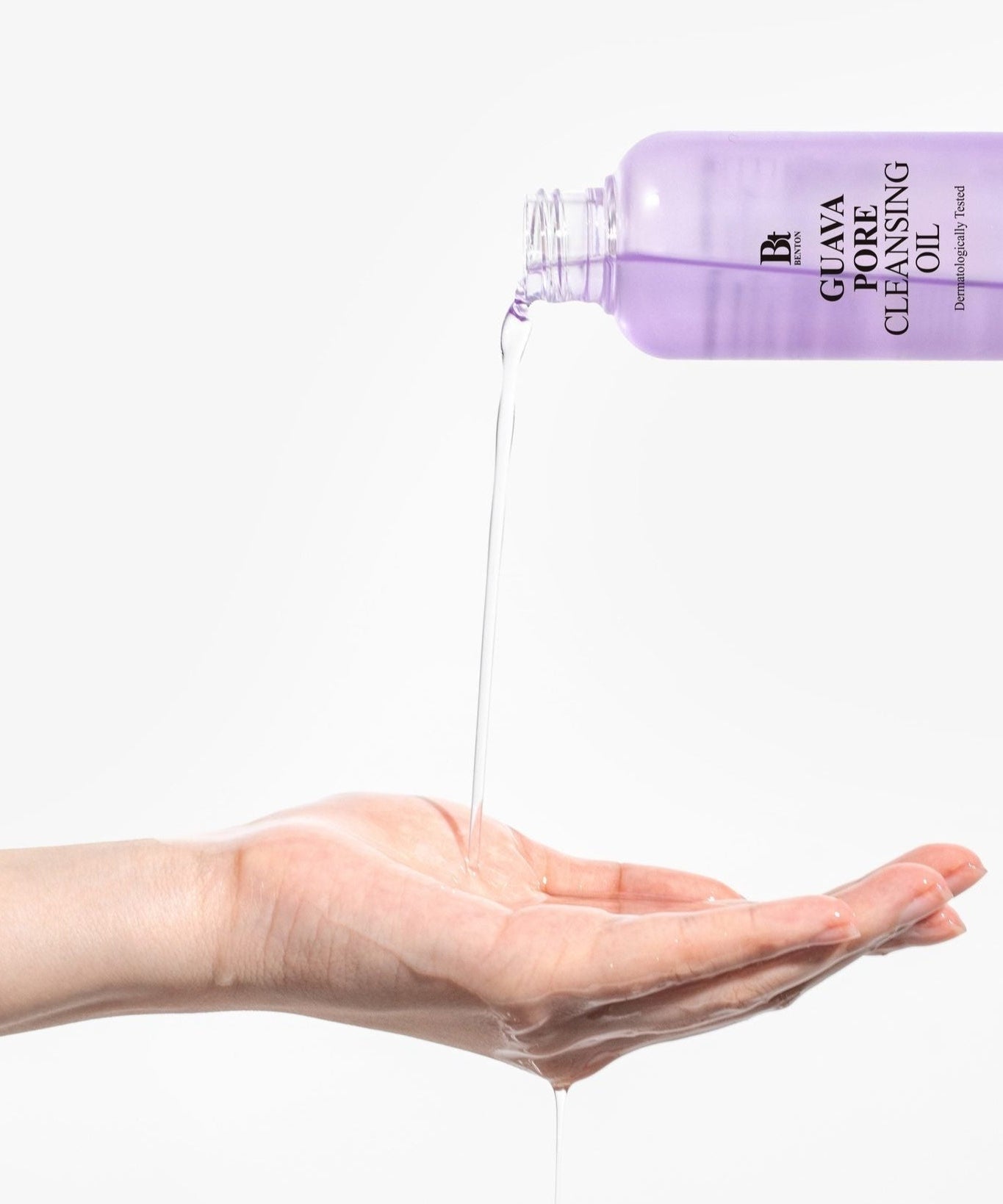BENTON Guava Blackhead Pore Cleansing Oil 200ml being poured onto a hand for skincare demonstration.