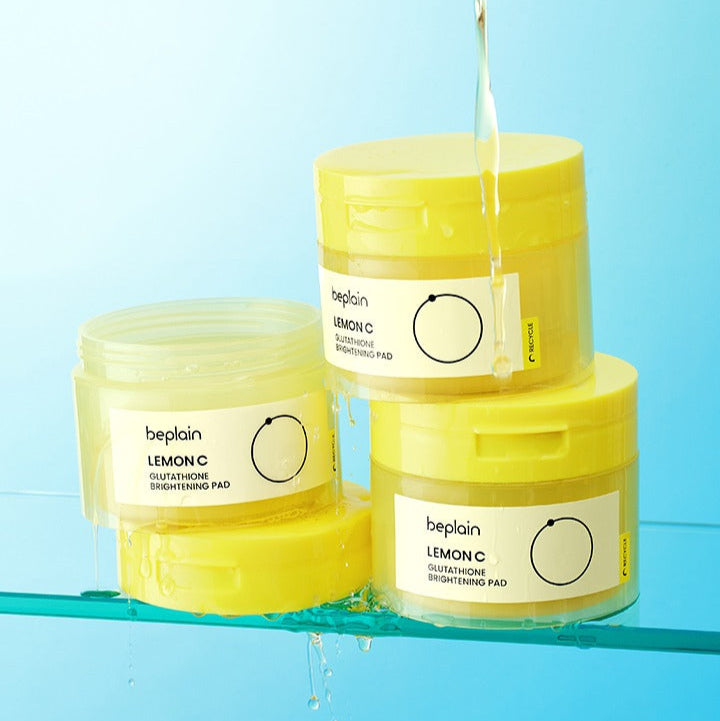 Three containers of BEPLAIN Lemon Seed Glutathione Whitenning Pads 70 Sheets on a blue surface with water splashes